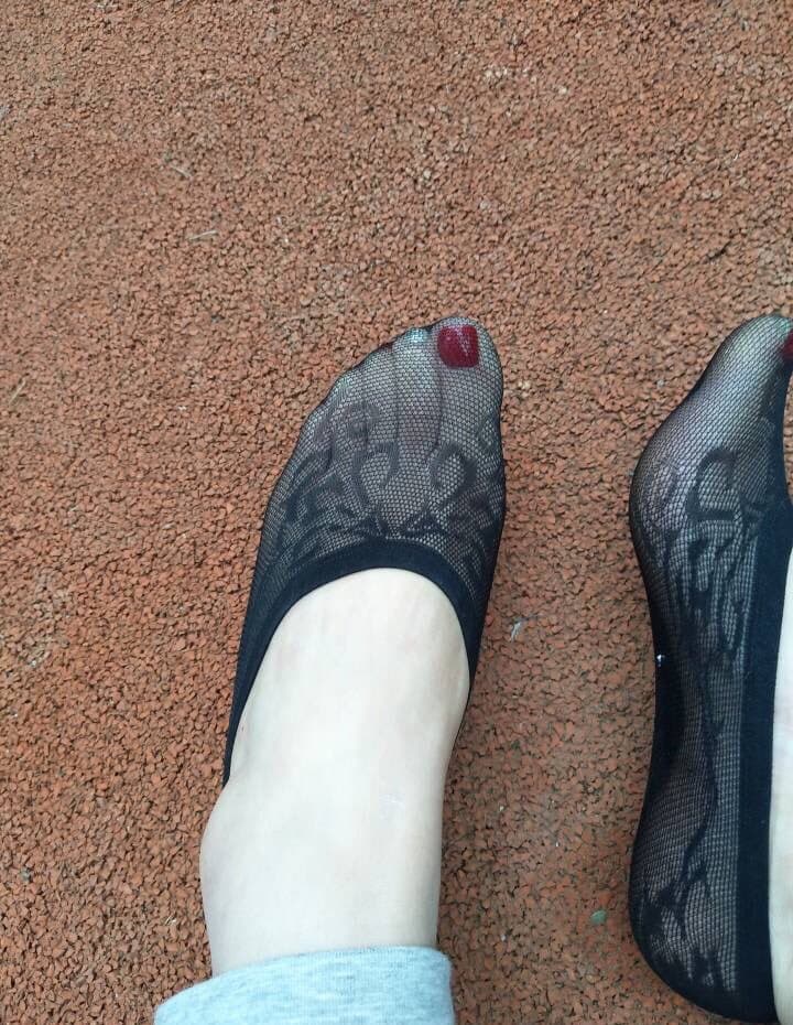 Overhead shot of feet resting on a teak deck, blue knit socks half-worn, sunlit skin and soft shadows creating intimate mood.